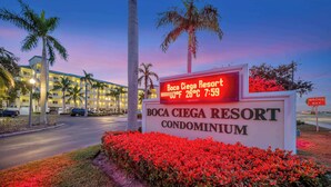Boca Ciega Resort Condominium sign with palm trees and a road in the background. - Bay View Condo & Private Balcony | Pool & Hot Tub (St. Petersburg)