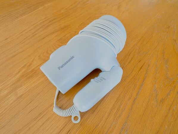 A white Panasonic hairdryer on a wooden surface. - CHITOSE CORPO (Tokyo)