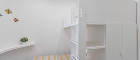 A child's room with a bunk bed, a small shelf with a plant, and wall decorations.