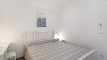 Ein Schlafzimmer mit einem Bett, einem Nachttisch, einer Lampe und einem an der Wand montierten Lichtschalter.