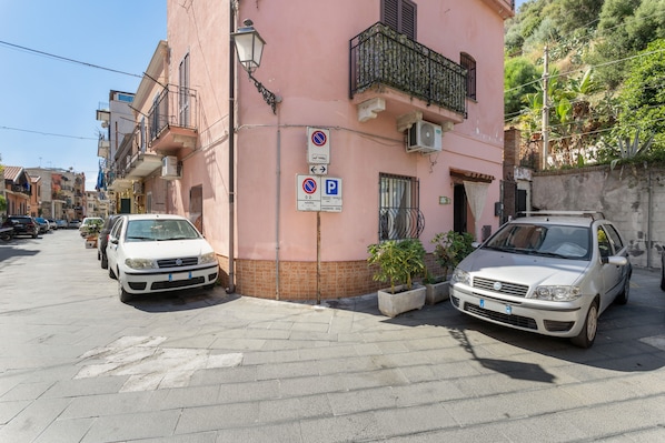 Una calle con coches aparcados y un edificio con un letrero de estacionamiento.