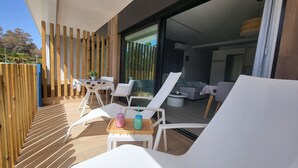 A sunlit outdoor seating area with white lounge chairs and a table, a wooden fence, and a view into the building. - Sunset Arguineguin by CanariasGetway (Mogán)