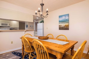 A dining area with a wooden table, chairs, a chandelier, and a painting on the wall.
