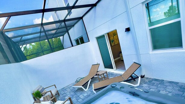 Een hottub met lounge stoelen en een patio met glazen wanden.