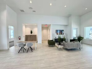 A spacious, modern living area with a dining table and chairs, a sofa, and a TV. - The Magical Retreat near Disney (Davenport)