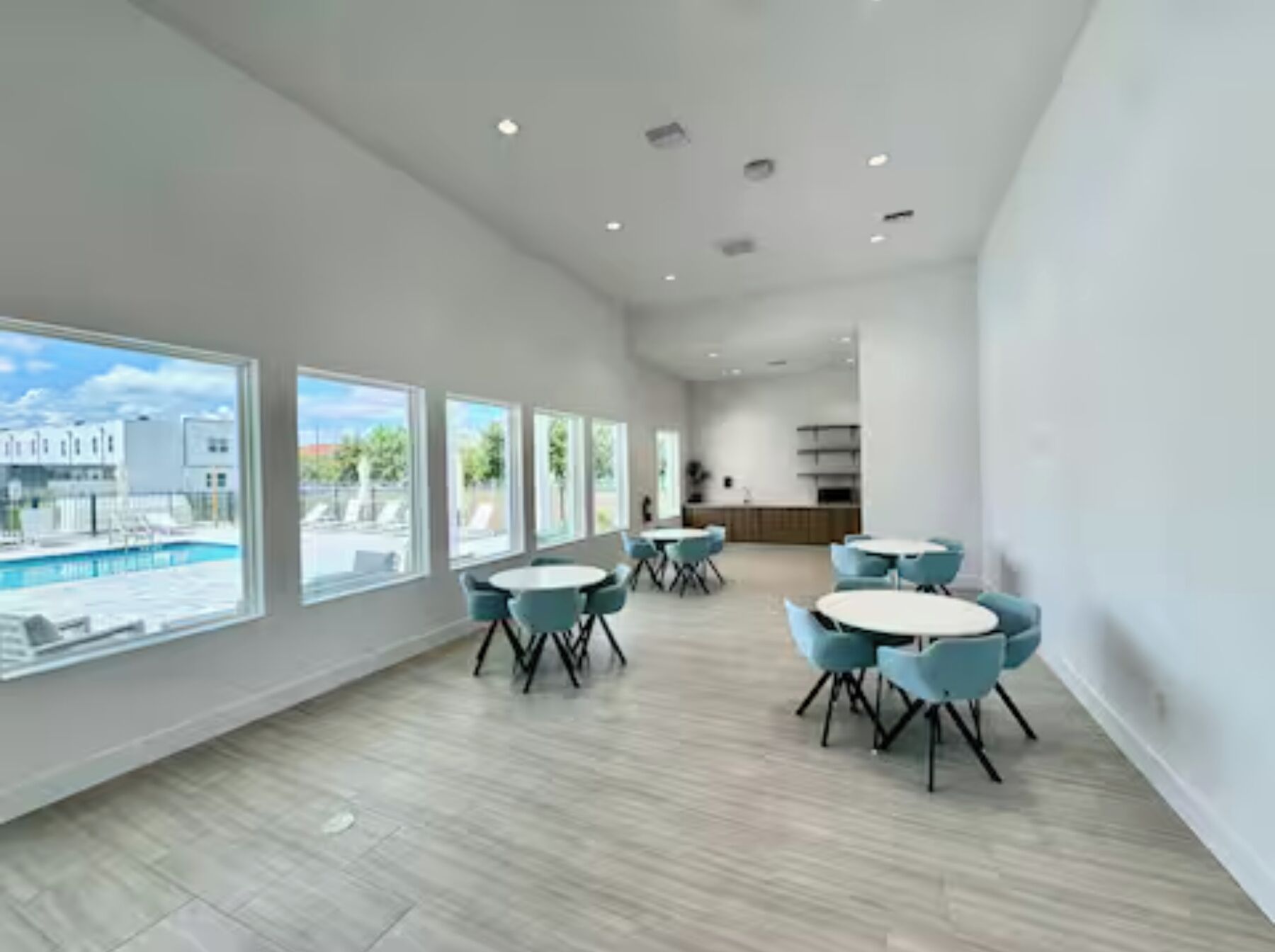 Una habitación amplia con grandes ventanales, vista a la piscina y muebles modernos.