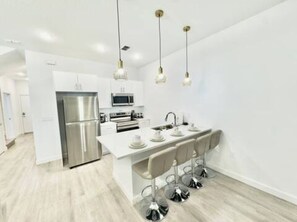 A modern kitchen with a central island, stainless steel appliances, and pendant lighting. - The Magical Retreat near Disney (Davenport)