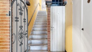 A staircase with a metal gate, a white door, and a brick archway. - Room 'Camera Matrimoniale' with Shared Garden, Wi-Fi and Air Conditioning (Chiavari)