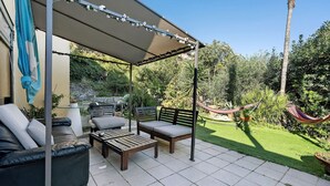 A covered patio area with outdoor furniture, a hammock, and lush greenery. - Room 'Camera Matrimoniale' with Shared Garden, Wi-Fi and Air Conditioning (Chiavari)