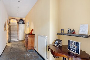 A hotel lobby with a stone floor, a wooden reception desk, a sign for a restaurant, and a staircase with a red railing. - Room 'Camera Matrimoniale' with Shared Garden, Wi-Fi and Air Conditioning (Chiavari)