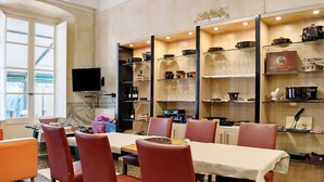 A dining area with a table set for six, surrounded by red chairs, with a kitchen area and a television in the background. - Room 'Camera Matrimoniale' with Shared Garden, Wi-Fi and Air Conditioning (Chiavari)