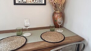 A dining table with two placemats, a vase with dried flowers, and two wine glasses.