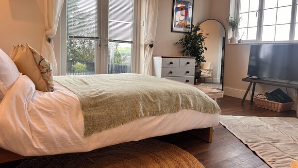 A bedroom with a bed, a dresser, a television, and a window with blinds.
