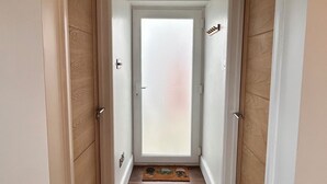 A hallway with wooden flooring, white walls, and a ceiling light fixture.