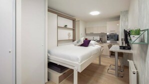 A compact bedroom with a bed, a desk, and a kitchenette. - Beautiful and modern studio for 2 near Bastille (Paris)