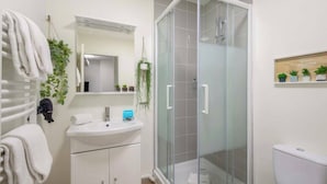 A bathroom with a glass shower enclosure, a white sink, and a toilet. - Beautiful and modern studio for 2 near Bastille (Paris)