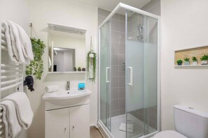 Ein Badezimmer mit Duschkabine aus Glas, einem weißen Waschbecken und einer Toilette.