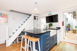 Una cocina moderna con una isla central, armarios azules y una escalera que sube a otro nivel.