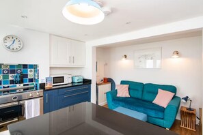 A modern kitchen with a central island, white cabinets, a microwave, and a stove. - Cozy One-Bedroom Apartment Near Brighton Seafront (Brighton)