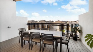 A balcony with a table and chairs, a potted plant, and a view of neighboring buildings. - Cherry St Retreat, Armstrong Creek (Armstrong Creek)