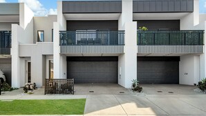 A modern two-story residential building with a flat roof, large garage doors, and a balcony with a metal railing. - Cherry St Retreat, Armstrong Creek (Armstrong Creek)