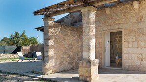 A stone building with a wooden pergola, a door, and a small outdoor seating area with two chairs. - Dimora Forticito (Marittima)