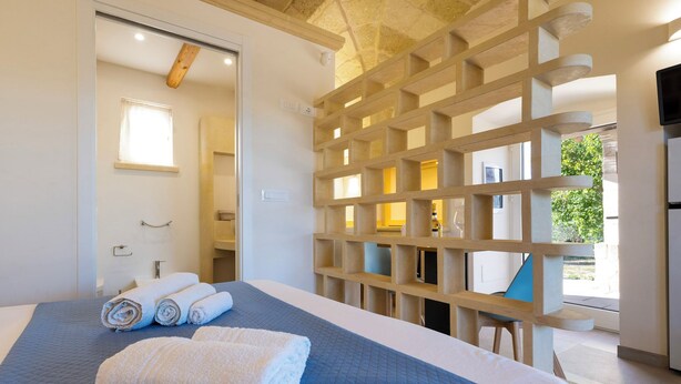 A hotel room with a large bed, a wooden partition, and a view of the outdoors. - Dimora Forticito (Marittima)