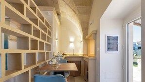A modern kitchen with a wooden table, blue chairs, and a built-in shelving unit. - Dimora Forticito (Marittima)