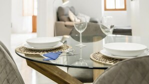 A dining table set with white plates, silverware, and two wine glasses. - Catalina Suites Downtown Valencia (València)
