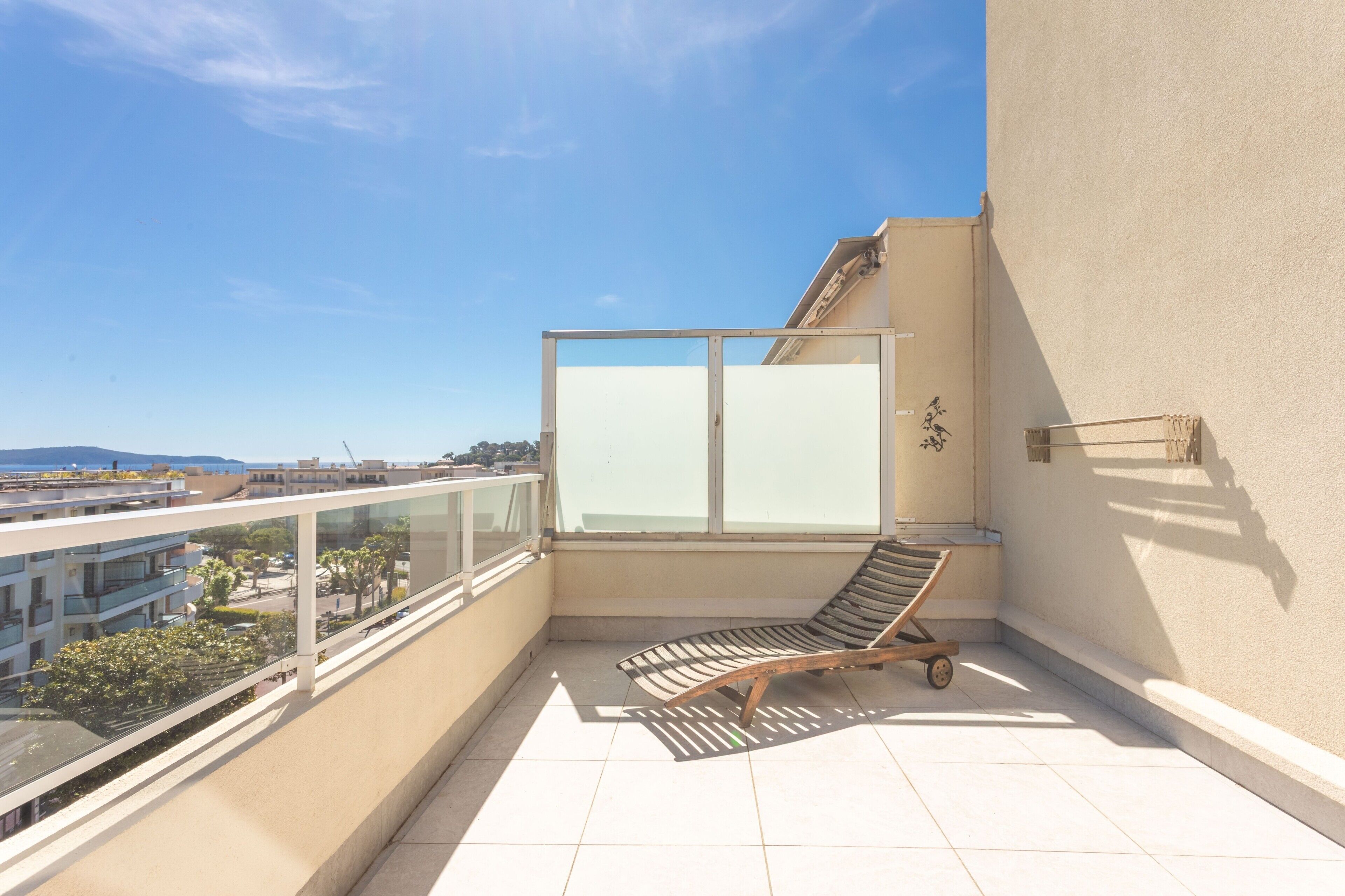 Un balcon avec un transat, une porte vitrée et une vue sur le paysage urbain.