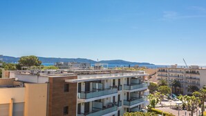 A multi-story hotel with balconies, a view of the sea, and a mountainous backdrop. - 2-Room Apartment with Sea View Terrace, Balcony, and Air Conditioning (Cavalaire-sur-Mer)