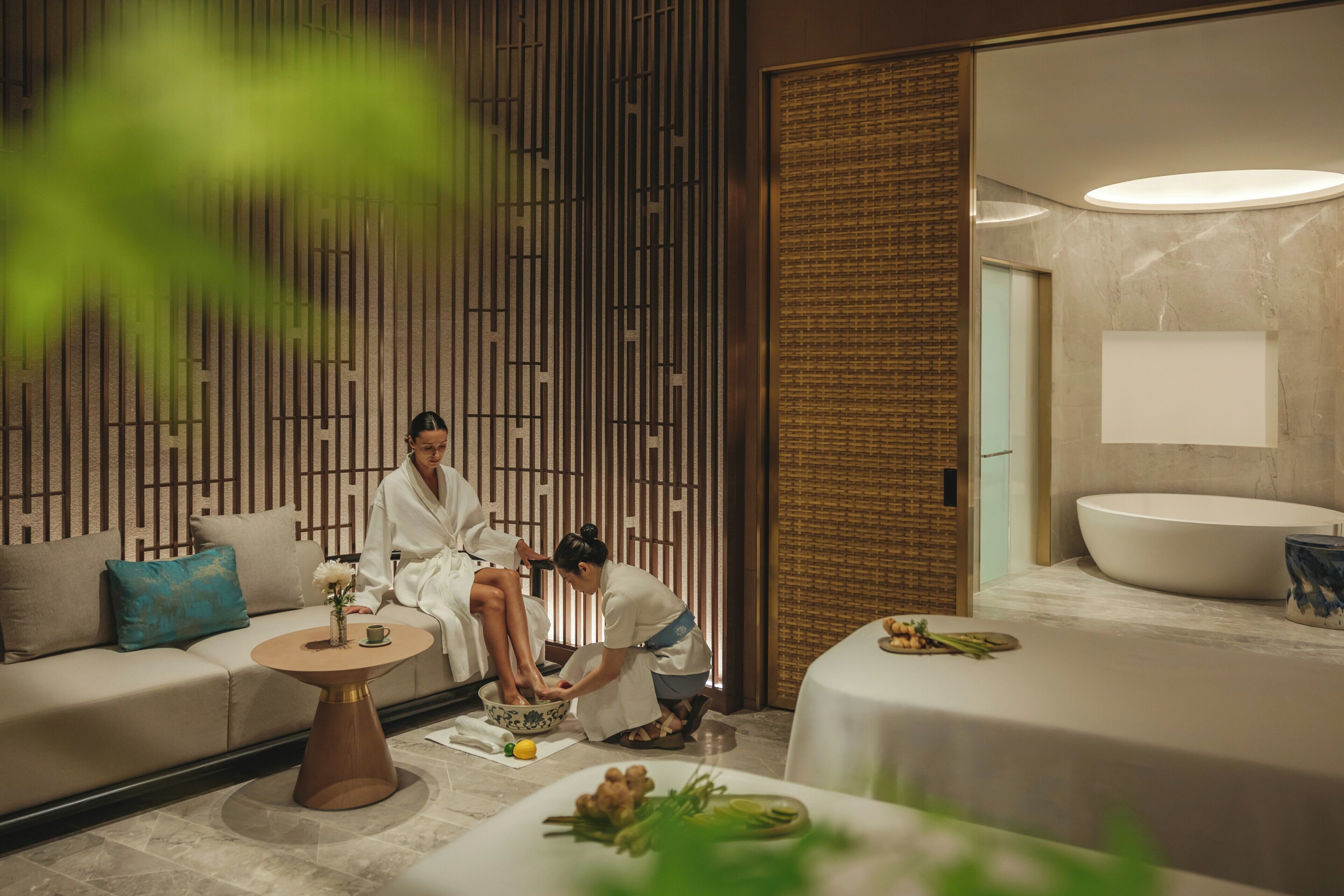 A spa room with a sofa, a round table with a bowl, a sink, and a wall with vertical lines.