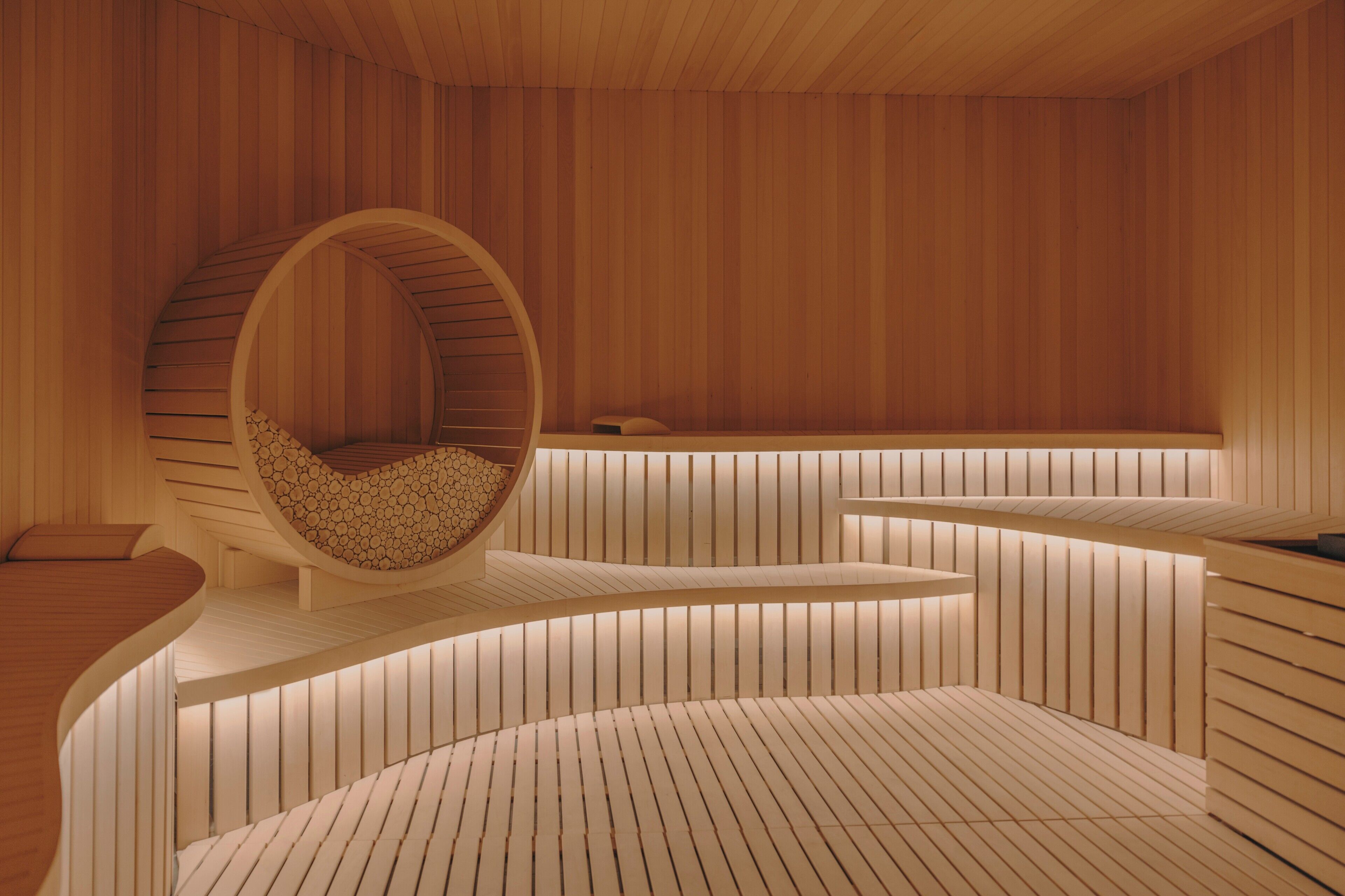 A modern interior with a circular seating area, wooden paneling, and a curved bench.