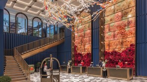 A lobby with a checkered floor, a staircase, and a reception desk with a floral backdrop. - Fairmont Hanoi (Hanoi)