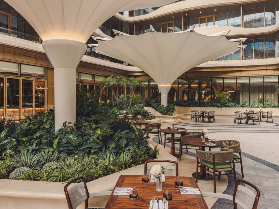 Un atrium à plusieurs niveaux, aménagé avec des tables, des chaises et une végétation luxuriante.