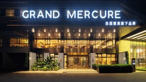 L’entrée d’un hôtel, avec une enseigne bien visible indiquant « GRAND MERCURE » et un escalier menant à l’étage supérieur.