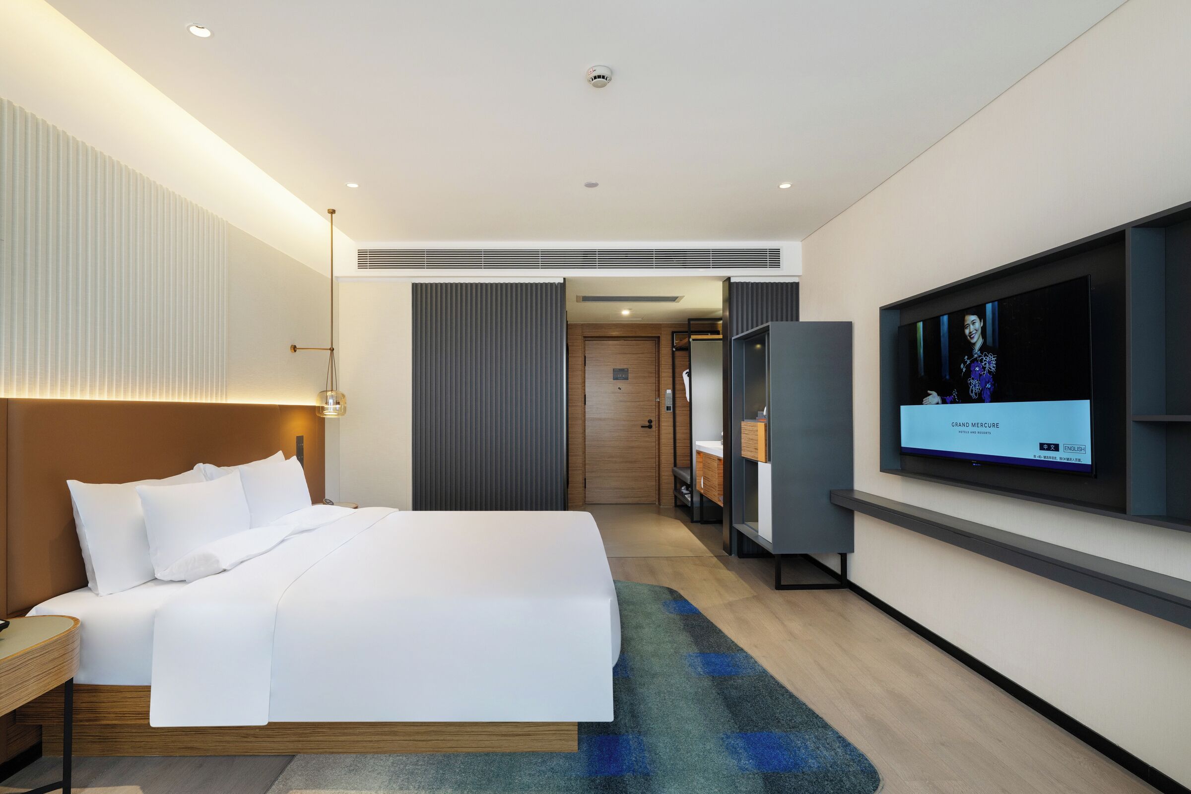 A modern hotel room with a large bed, a flat-screen TV, and a walk-in closet.