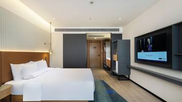 A modern hotel room with a large bed, a flat-screen TV, and a walk-in closet.