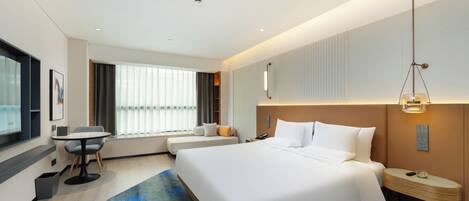 Une chambre d’hôtel moderne, dotée d’un grand lit, d’un bureau et d’une fenêtre avec stores.