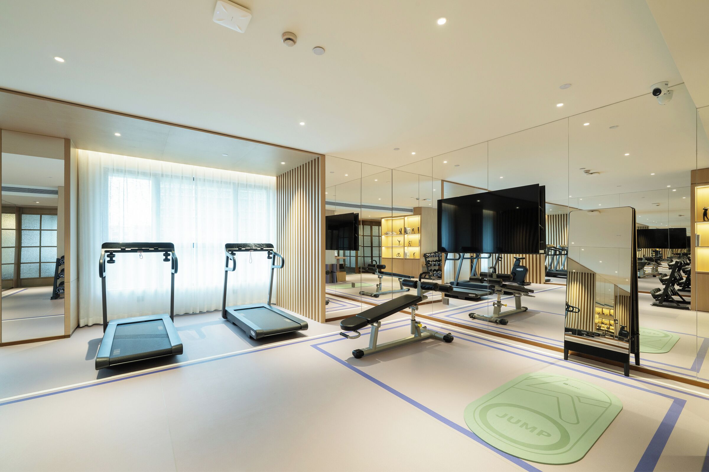 A modern gym with treadmills, a bench press, and mirrored walls.
