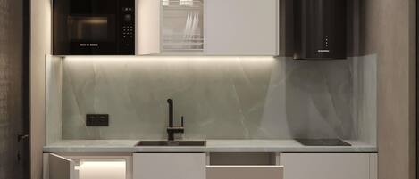 A modern kitchen with a built-in microwave, a stainless steel range hood, and a white marble backsplash.