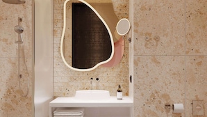 Une salle de bain moderne avec une douche à l’italienne, un lavabo blanc avec un miroir et des toilettes.