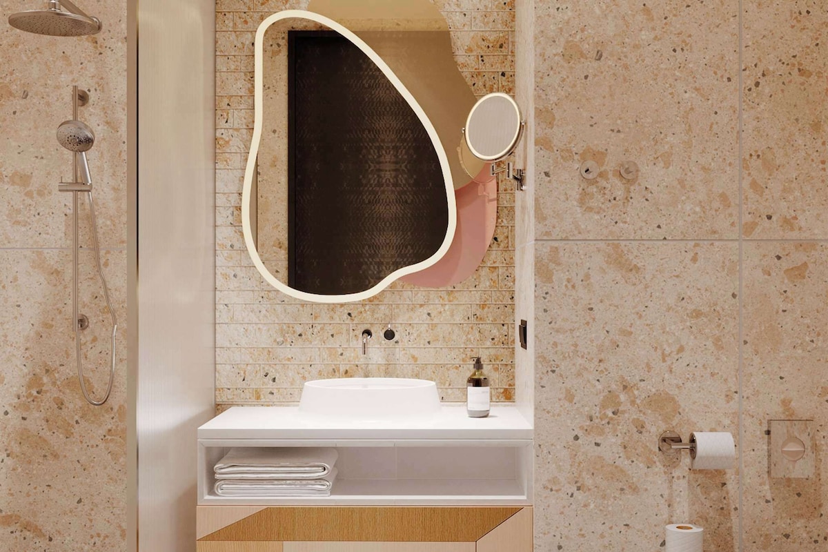 A modern bathroom with a freestanding shower, a white sink with a mirror, and a toilet.