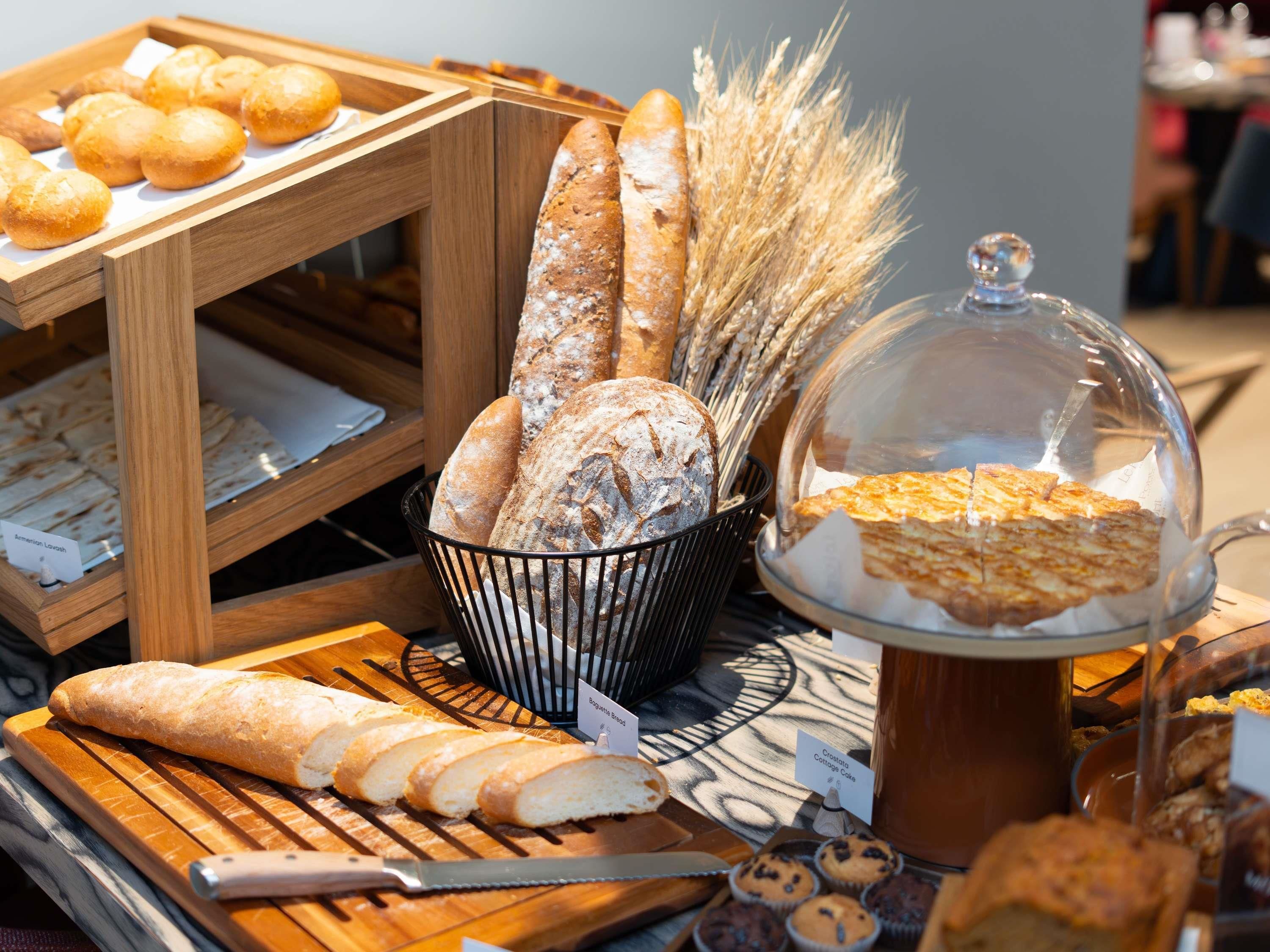 Eine Bäckereireihe mit verschiedenen Broten und Gebäck, darunter ein Brotlaib und ein Korb mit Brötchen.