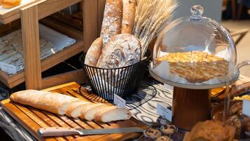 Eine Bäckereireihe mit verschiedenen Broten und Gebäck, darunter ein Brotlaib und ein Korb mit Brötchen.