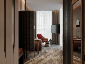 A hotel room with a large window, a flat-screen TV, a red chair, a small table, and a sofa. - Mövenpick Yerevan (Yerevan)