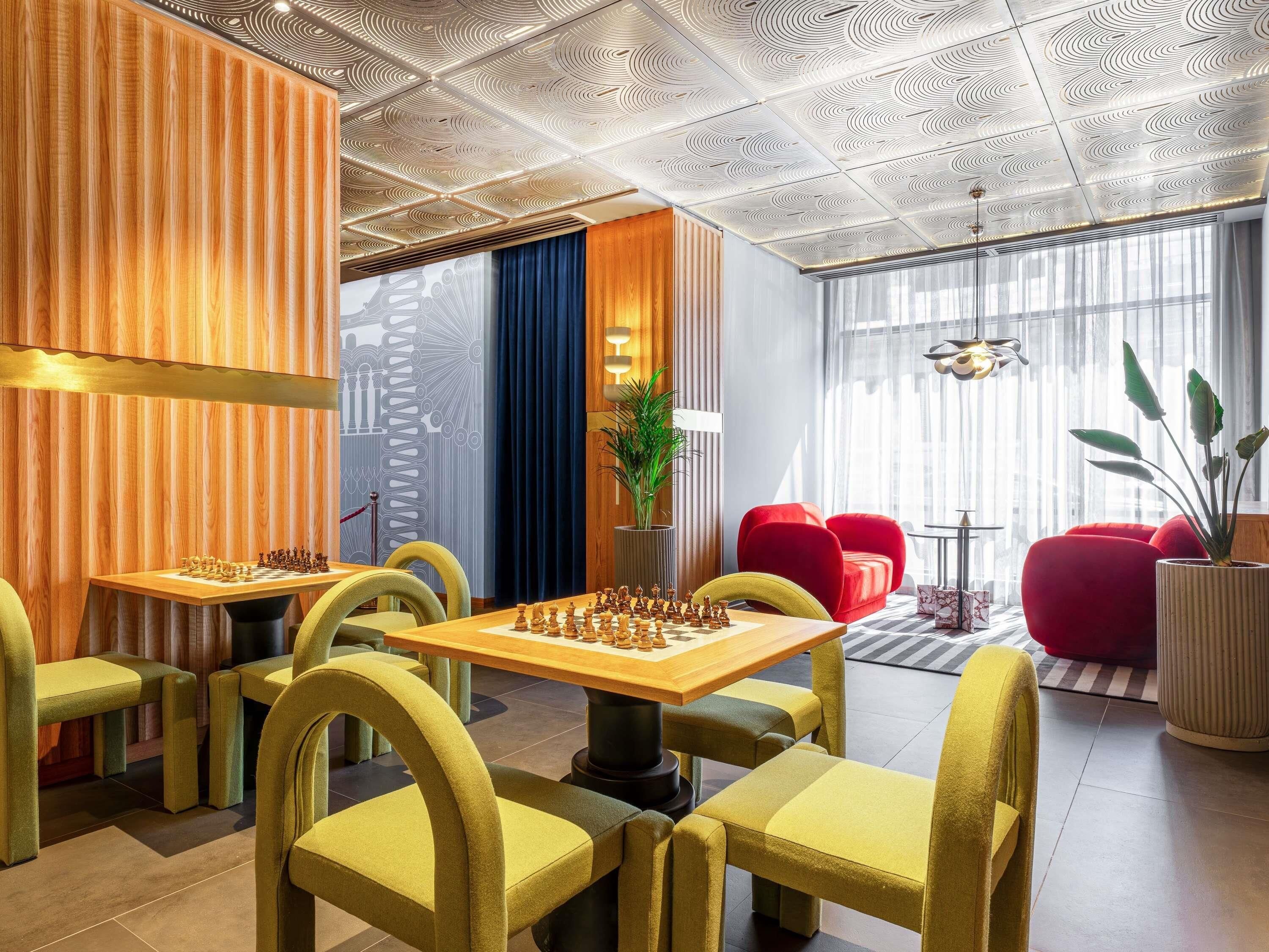 A modern lounge area with chess tables, comfortable seating, and a decorative ceiling.