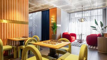 A modern lounge area with chess tables, comfortable seating, and a decorative ceiling.