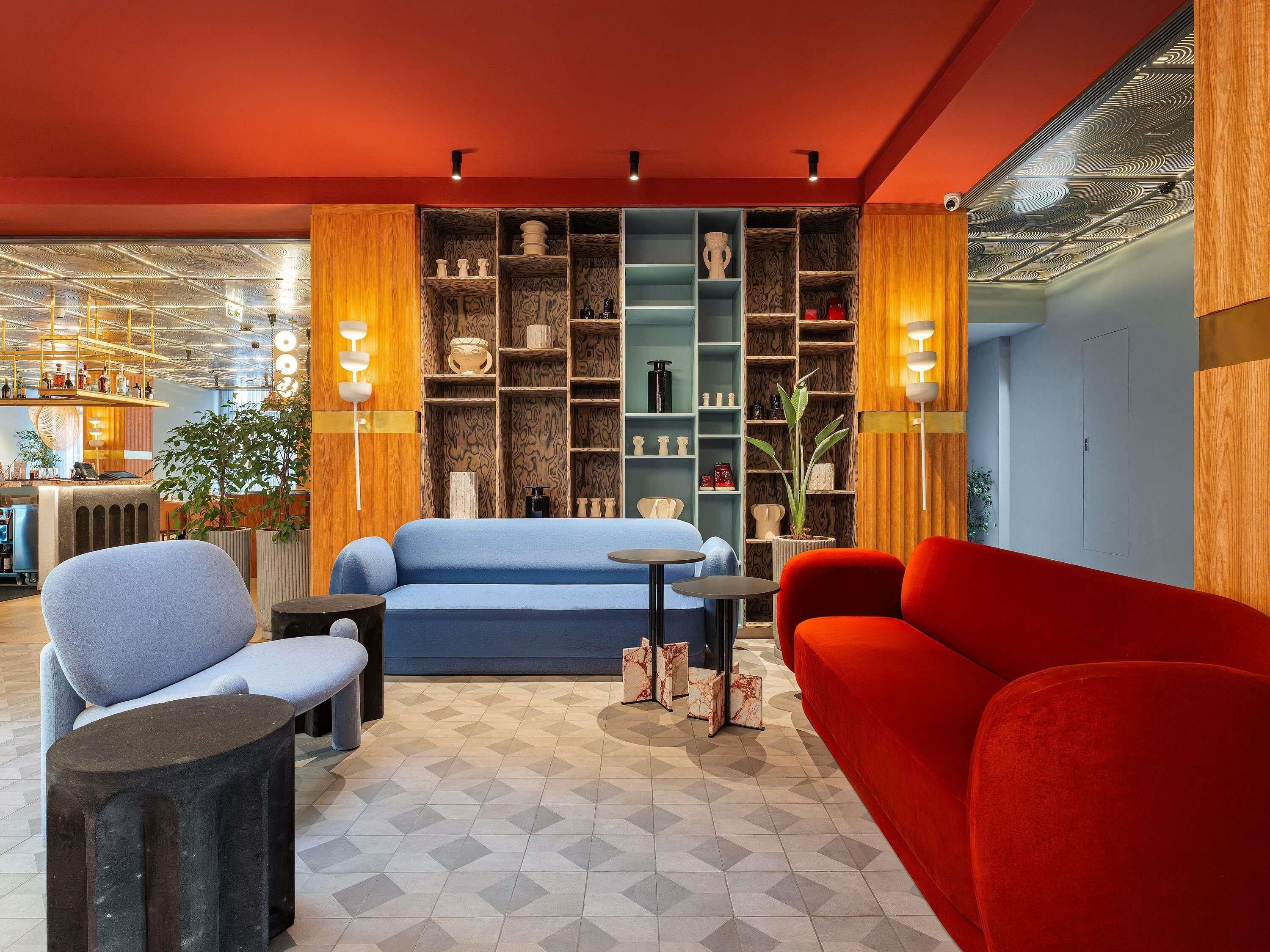 Een modern interieur met een blauwe bank, een rode fauteuil en een vloer met een patroon.