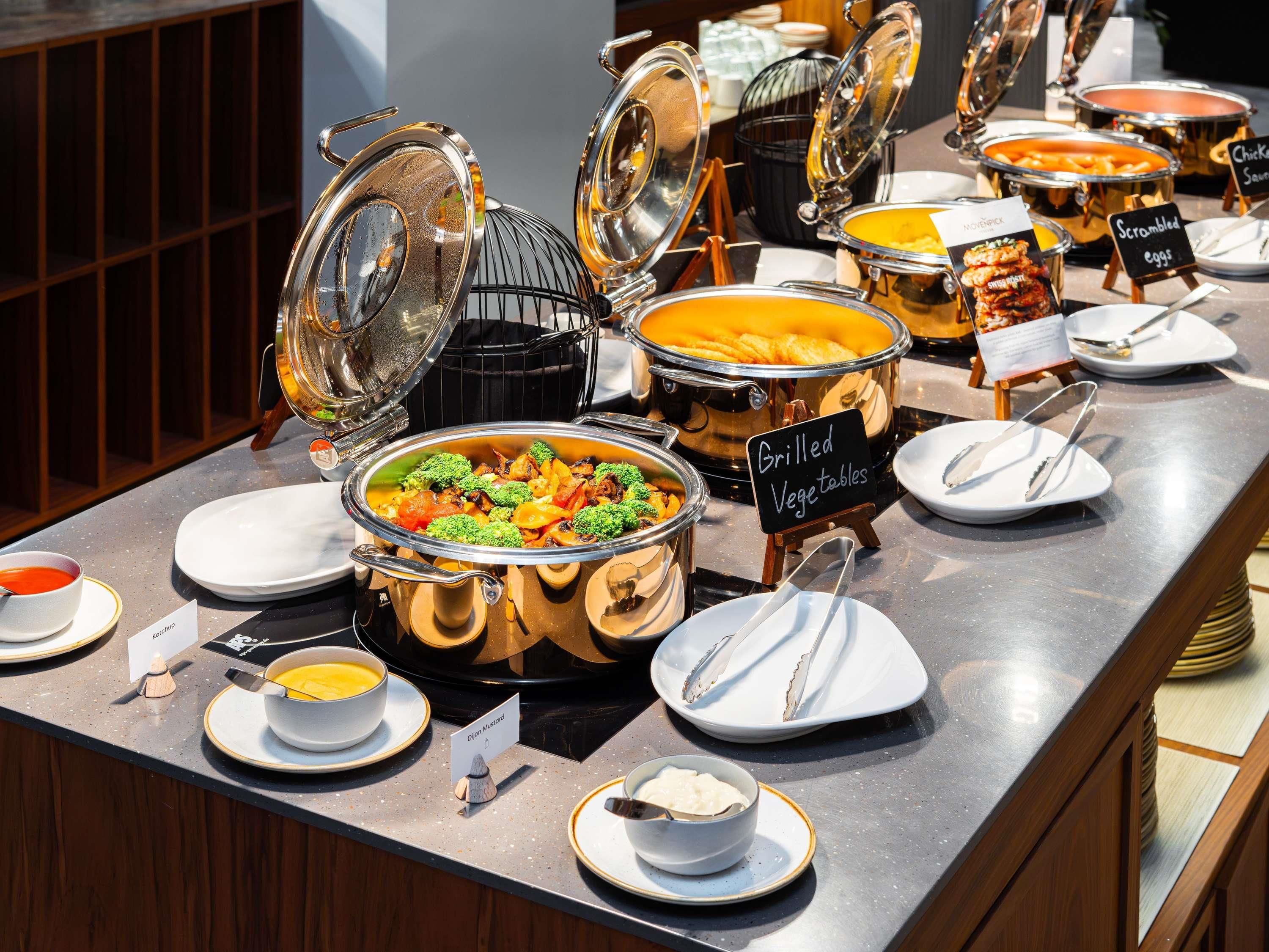 A buffet setup with various food items and serving utensils.
